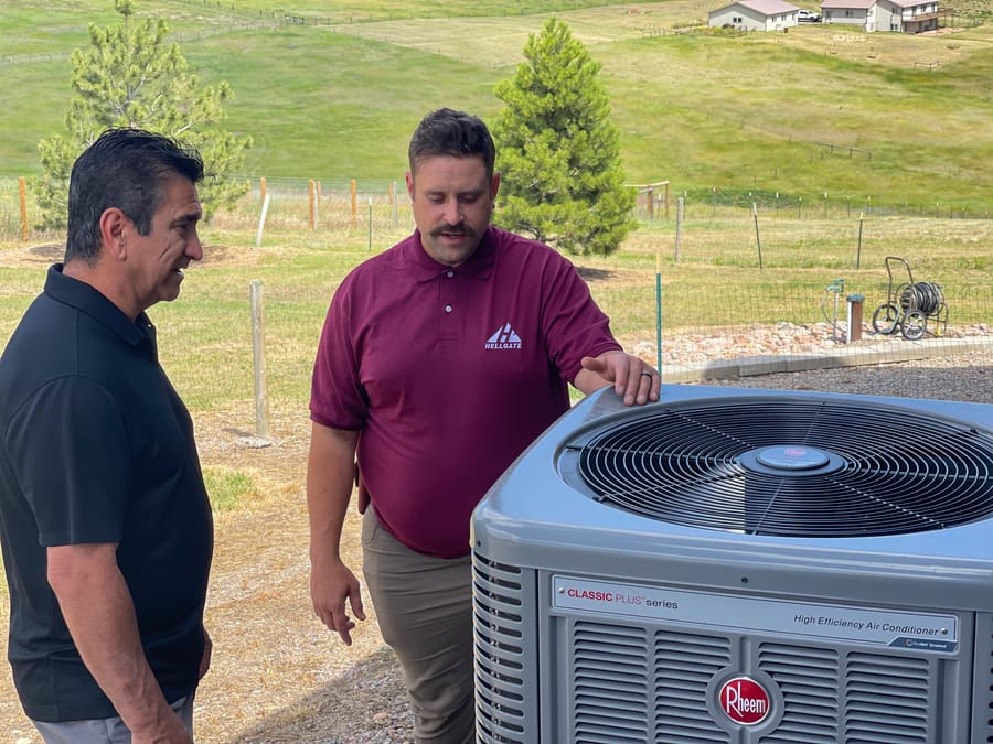 HVAC technician standing in front of AC unit.