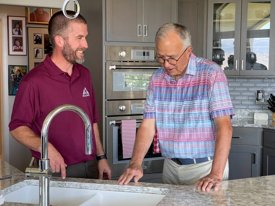 Hellgate plumber standing in front of kitchen sink with client.